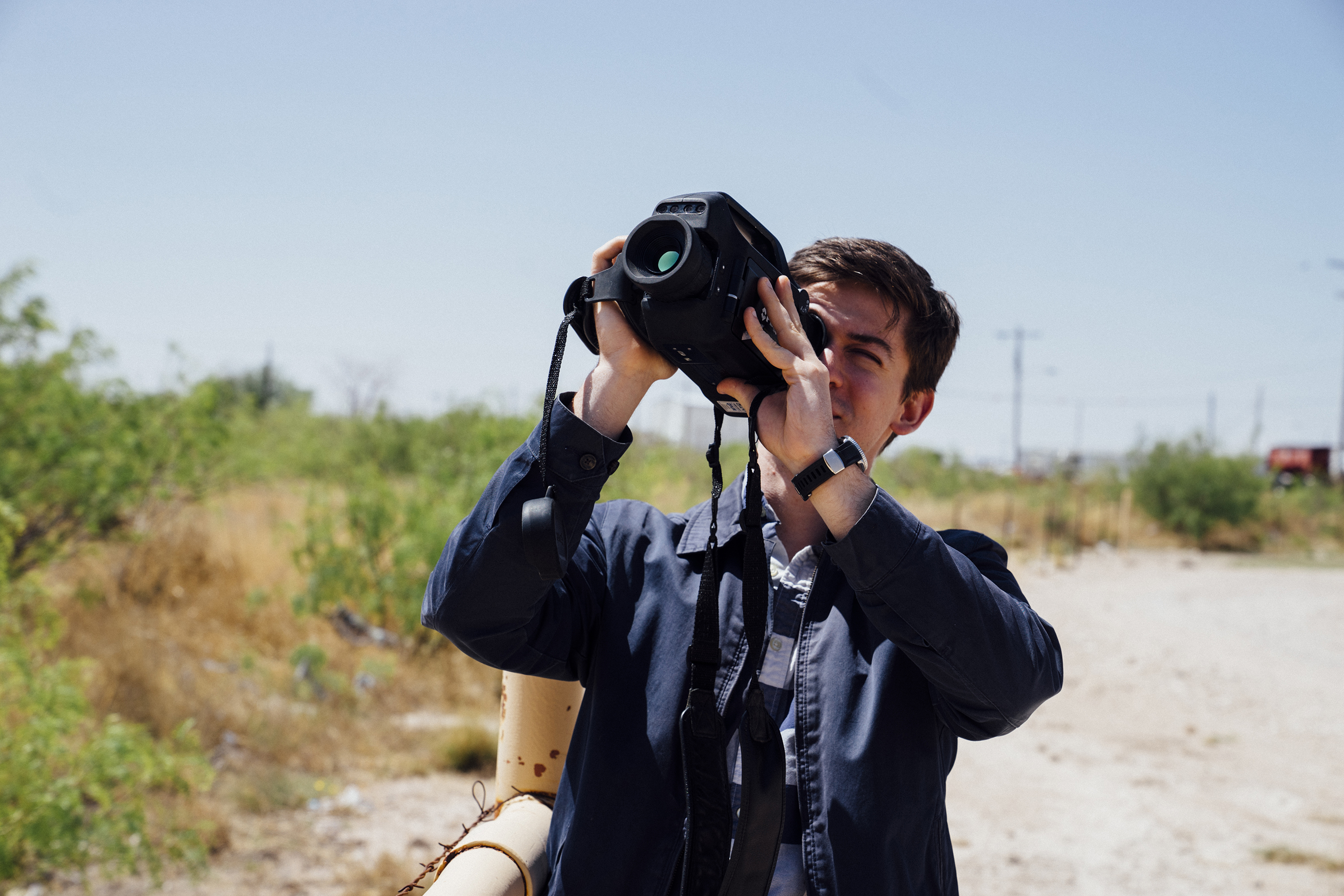 A researcher uses a handheld imaging device outdoors.