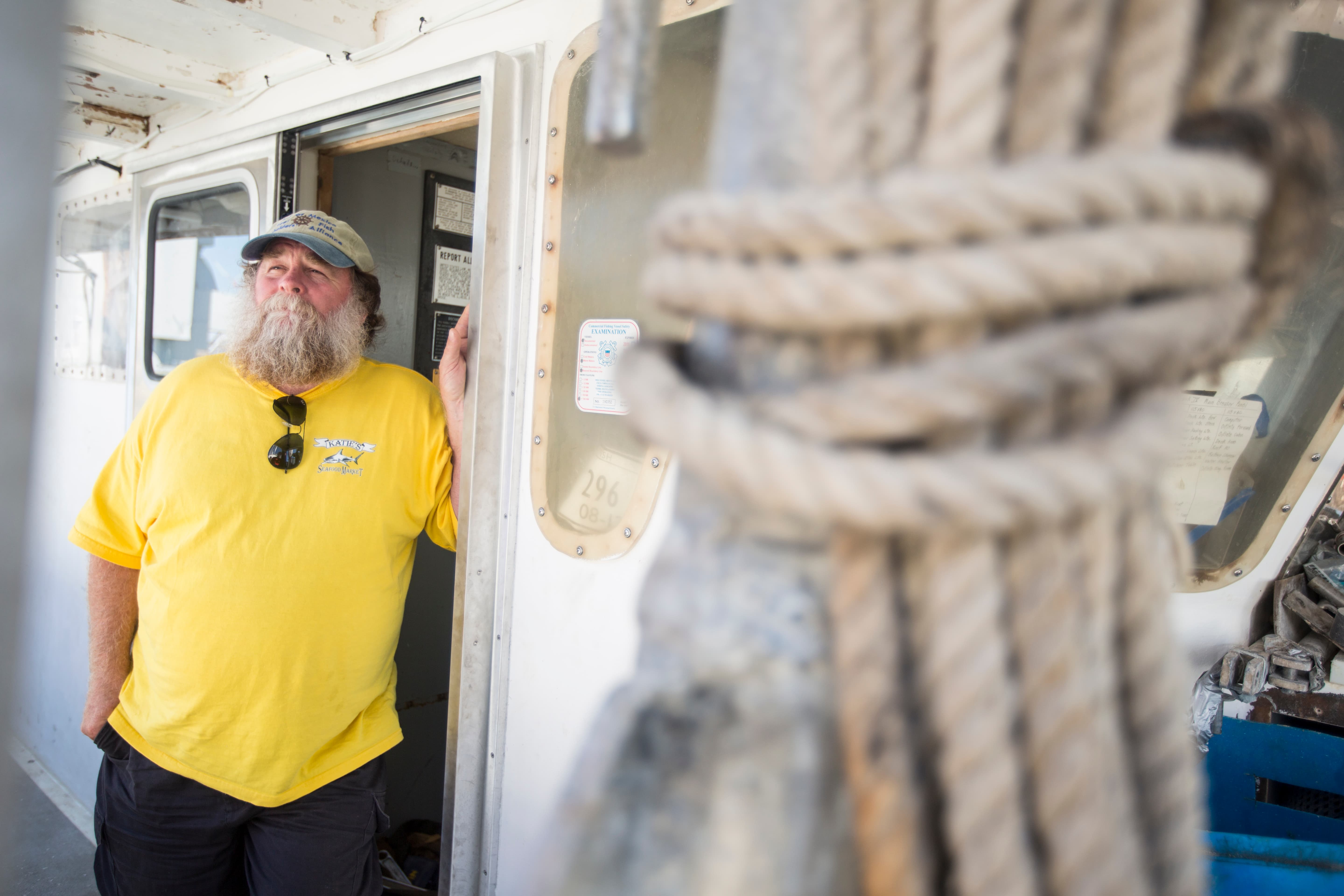 Keith “Buddy” Guindon standing at the door to a fishing boat with a rope tied up in the foreground
